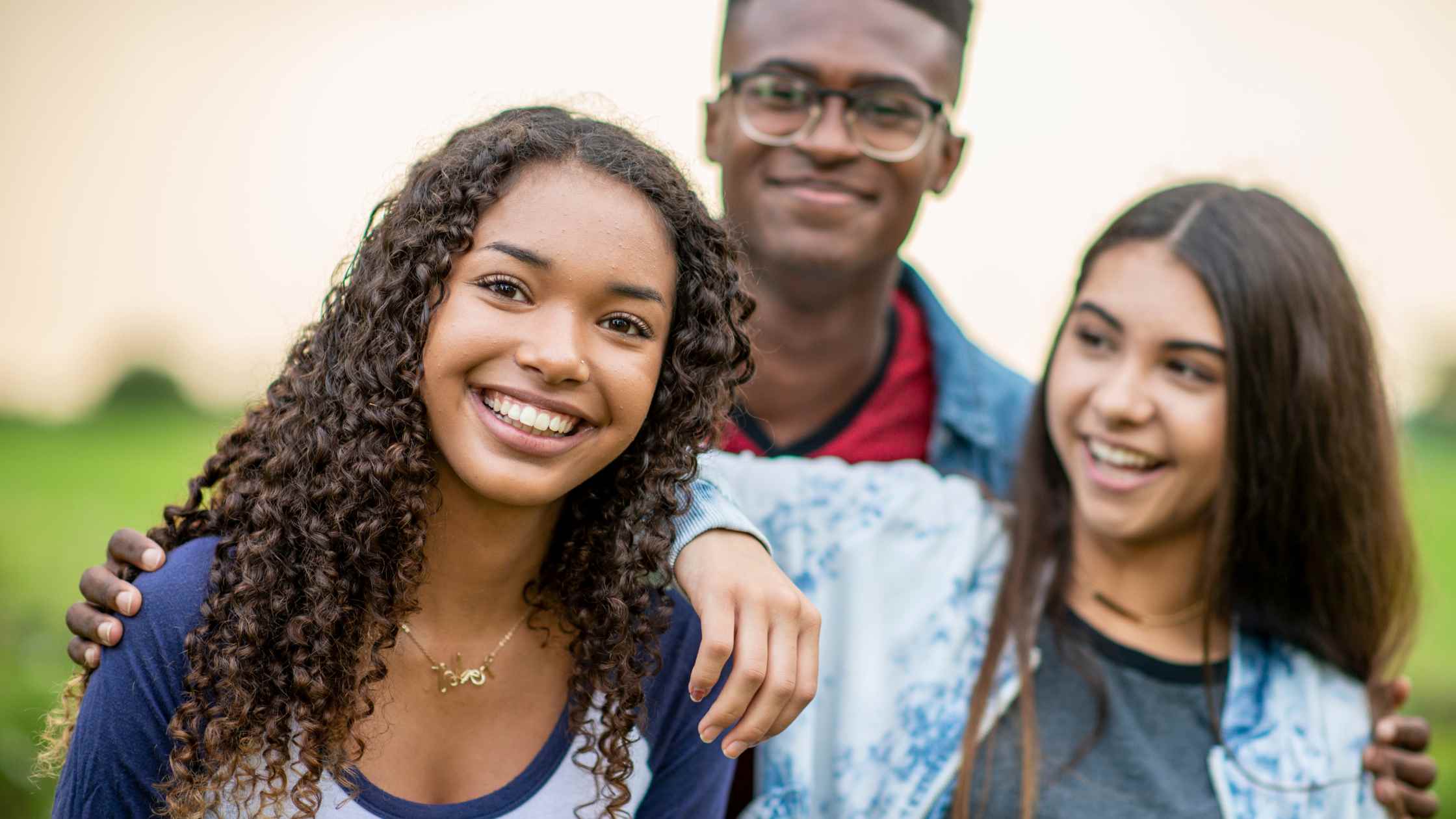 Child Custody Three teenagers stand out in the open with smiles on their faces.